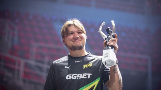 S1mple, en Counter-Strike-spiller, iført en NAVI-trøje og løfter et trofæ på et stadion.